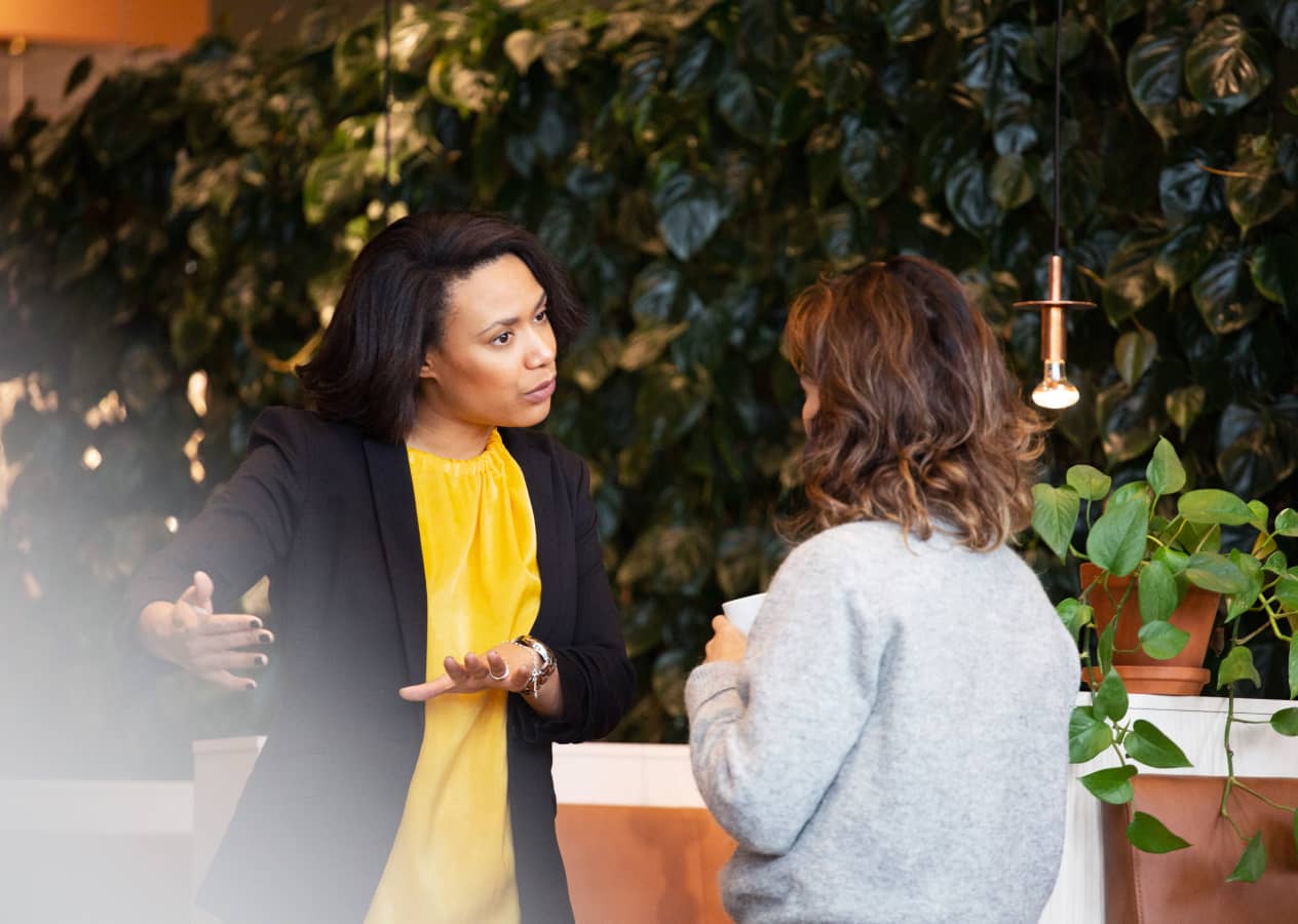 Two professionals in deep conversation in front of a living wall and surrounded by plants